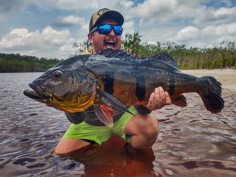 An angler in the shallows with a trophy peacock bass