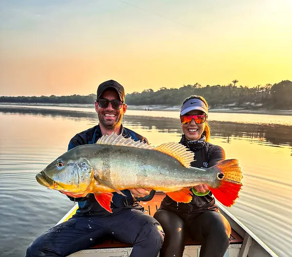 Two anglers and a peacock bass at sunset